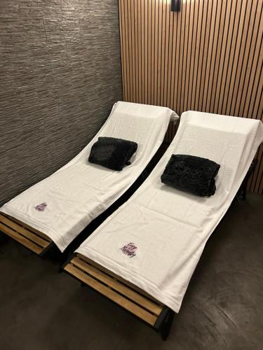 Duas camas com lençóis brancos e toalhas pretas em Cosy@Beauty em Petit-Rechain