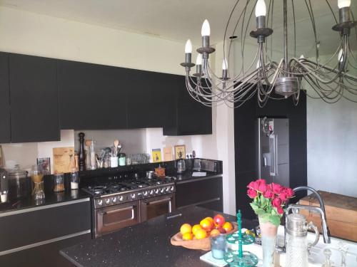 une cuisine avec des armoires noires et une table avec des fruits dans l'établissement Chambres 2 personnes dans notre maison Girondine, à Saint-Martin-de-Lerm