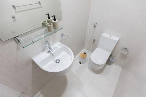 a white bathroom with a toilet and a sink at COLIFE 21 floor, 7 min drive from Dubai Mall 136 in Dubai