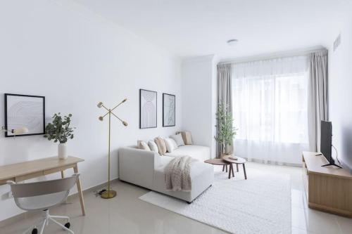 a white living room with a white couch and a tv at COLIFE 21 floor, 7 min drive from Dubai Mall 136 in Dubai