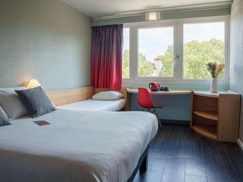 ein Hotelzimmer mit 2 Betten, einem Schreibtisch und einem Fenster in der Unterkunft Ibis Alès Centre Ville in Alès