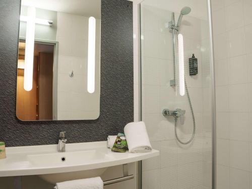 a bathroom with a sink and a shower with a mirror at Ibis Alès Centre Ville in Alès