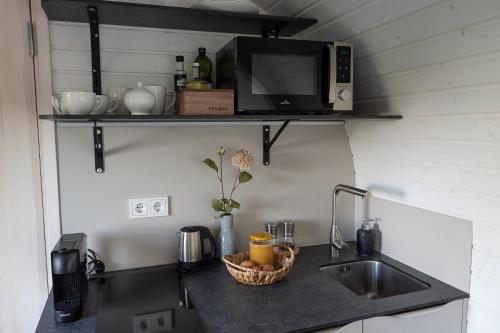 a kitchen counter with a sink and a microwave at Glamping Skrytín in Dobkovice
