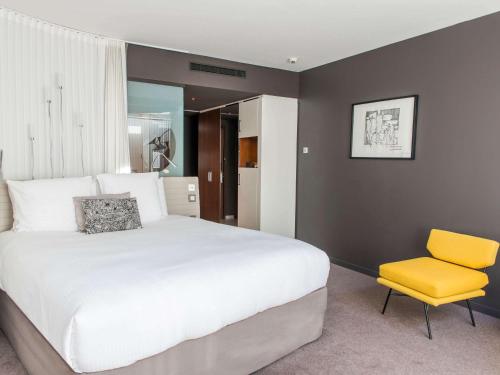 sypialnia z białym łóżkiem i żółtym krzesłem w obiekcie Molitor Hôtel & Spa Paris - MGallery Collection w Paryżu