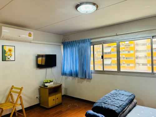 Schlafzimmer mit einem Bett, einem TV und einem Stuhl in der Unterkunft Condo Poppular T8 fl.7 in Thung Si Kan
