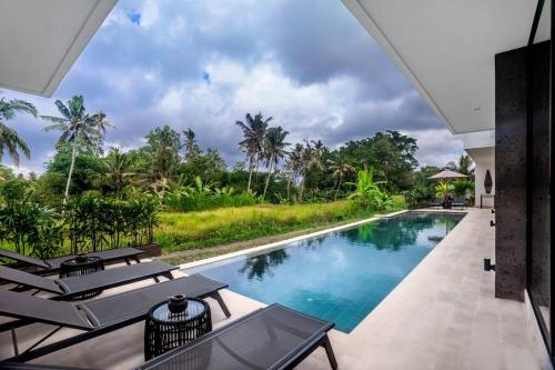 - une piscine avec des chaises longues à côté d'un complexe dans l'établissement The R Villa Cereme - nature, quite, luxurious, à Tegalalang