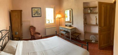 une chambre avec un lit, un bureau et un miroir dans l'établissement Auberge de Mazan, à Mazan