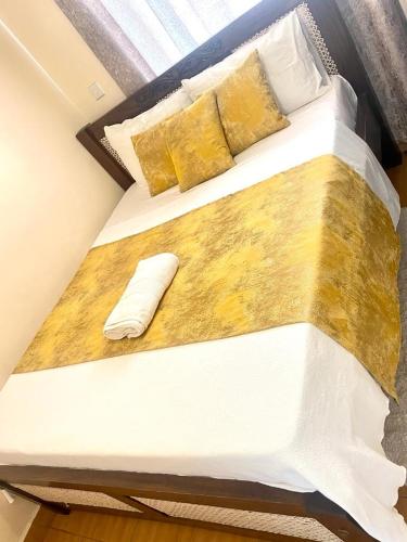 a large bed with white sheets and gold pillows at Jantabase Homes kisumu in Kisumu