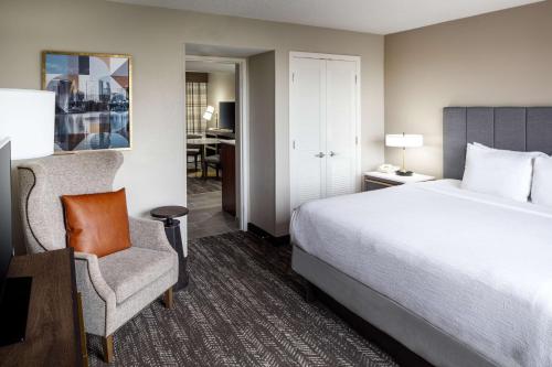 奥兰多Embassy Suites by Hilton Orlando North的一间带床和椅子的酒店房间