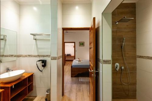 a bathroom with a sink and a shower and a bed at Anse Lazio Lodge in Anse Lazio