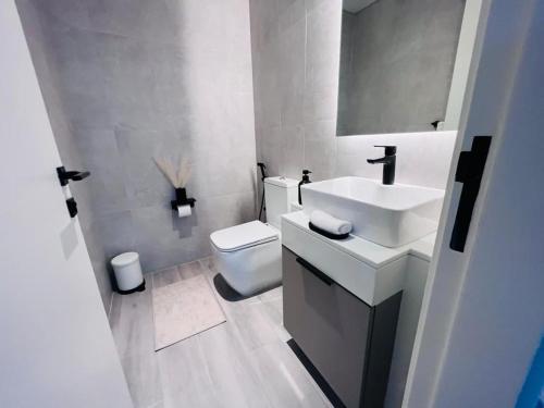 a white bathroom with a sink and a toilet at Dar Alsalam - Premium and Spacious 1BR With Balcony in Noor 2 in Dubai