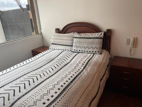 キトにあるHermosa Suite inteligente con Jacuzziのベッドルーム1室(木製ヘッドボードと枕付きのベッド1台付)