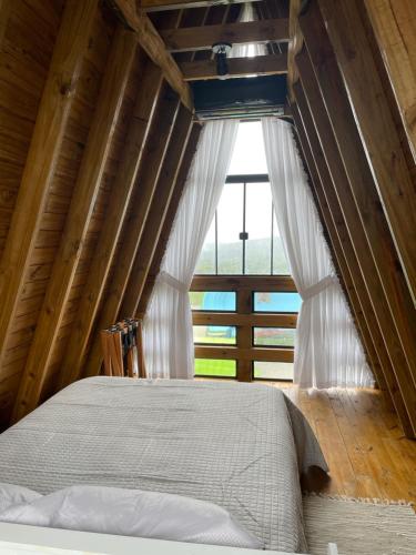 a bedroom with a bed and a large window at Pousada Portal dos campos in Ponta Grossa