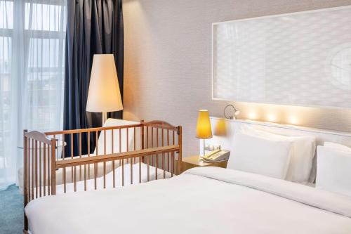 a hotel room with two beds and a crib at Radisson Residences, Zavidovo in Zavidovo