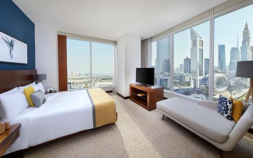 voco Dubai, an IHG Hotel في دبي: فندق كبير غرفه بسرير كبير واريكه