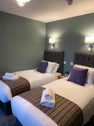a hotel room with two beds with purple pillows at The 1645 Inn in Nairn