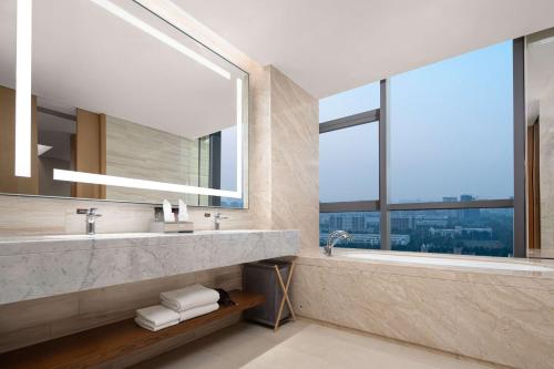 baño con 2 lavabos y ventana grande en Hilton Garden Inn Zibo Zhangdian, en Zibo