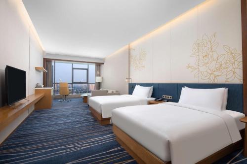 una camera d'albergo con due letti e una televisione di Hilton Garden Inn Zibo Zhangdian a Zibo