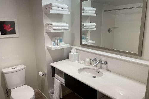 a bathroom with a sink and a toilet and a mirror at Chateau Fredericton, Trademark Collection by Wyndham in Fredericton