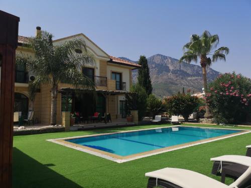 uma casa com piscina com montanhas ao fundo em Stunning Private Villa - Beautiful Gardens & Pool em Lapithos