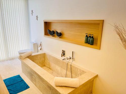 a bathroom with a large stone tub with bottles on the wall at Yuka residence in Koh Samui 