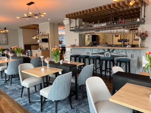 un restaurante con mesas y sillas y un bar en Deichhotel Rose, en Juist