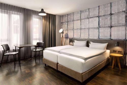 Un dormitorio con una gran cama blanca y una mesa. en Vienna House Easy by Wyndham Bremen City Apartments, en Bremen