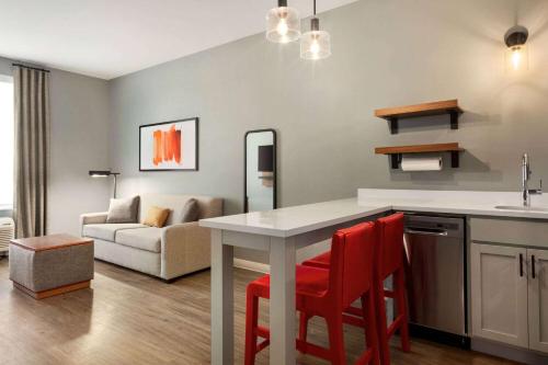 cocina y sala de estar con mesa y sillas rojas en Hawthorn Extended Stay by Wyndham Mount Laurel Moorestown, en Mount Laurel