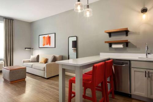 a kitchen and living room with a table and red chairs at Hawthorn Extended Stay by Wyndham Mount Laurel Moorestown in Mount Laurel