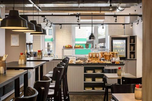 a kitchen with tables and chairs in a restaurant at Vienna House Easy by Wyndham Bremen City Apartments in Bremen