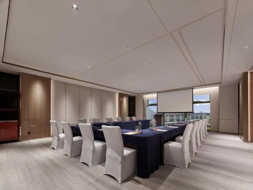 a conference room with a long table and white chairs at DoubleTree By Hilton Cangnan in Cangnan