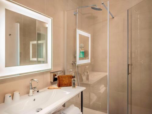 een badkamer met een wastafel en een glazen douche bij Novotel Orléans Centre Gare in Orléans