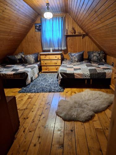 1 dormitorio con 2 camas y suelo de madera en Chata Vlkolínec, en Ružomberok