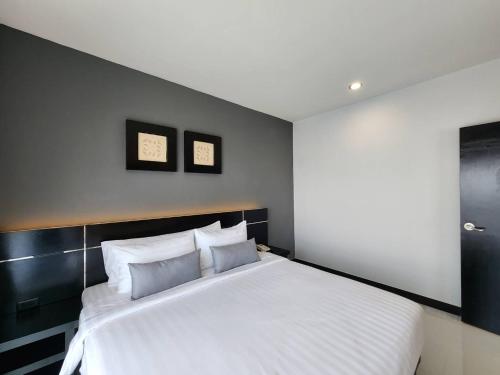 a bedroom with a large white bed with three pillows at LHC HOTEL AND RESORT in Pattaya Central