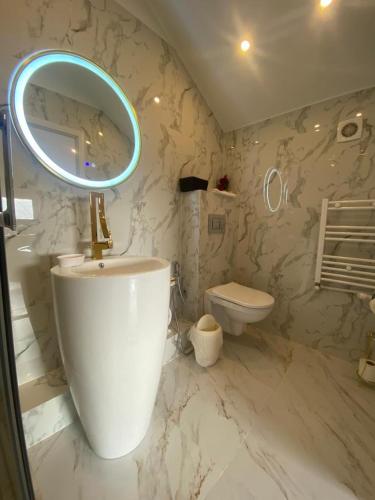 a bathroom with a mirror and a sink and a toilet at Ami Residence Bucharest Airport&Therme&Parking in Otopeni