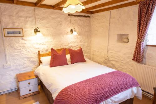 Swallow Cottage في بريدجيند: غرفة نوم عليها سرير ومخدات حمراء