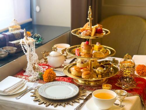 a table with a tray of pastries and cups of tea at Taj 51 Buckingham Gate Suites and Residences in London