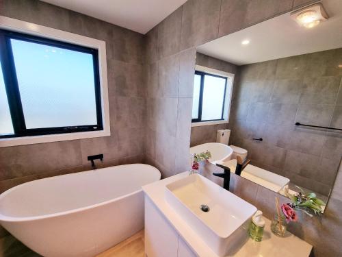 uma casa de banho com uma banheira branca e um lavatório. em Brand new house - Mordern home and great location em Sunshine