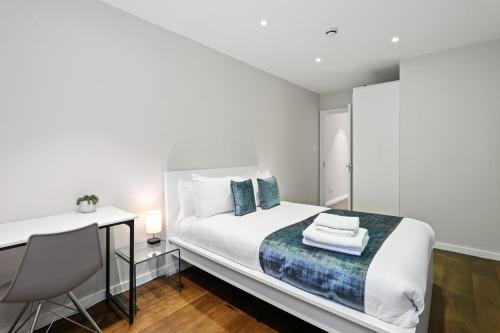 a white bedroom with a bed and a desk at Spacious 1 bedroom flat in London