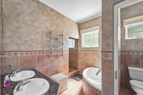 een badkamer met 2 wastafels, een bad en een toilet bij Seaside Villa - 1 La Mer in Hout Baai