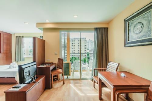 巴東海灘的住宿－Bauman Residence Patong, Phuket，配有一张床和一张书桌的酒店客房
