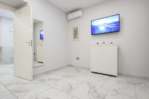 Dieses weiße Zimmer verfügt über einen TV an der Wand. in der Unterkunft House giovy in Neapel