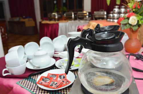 Siyanco Holiday Resort في بولوناروا: إبريق شاي موضوع على طاولة عليها أطباق وأكواب