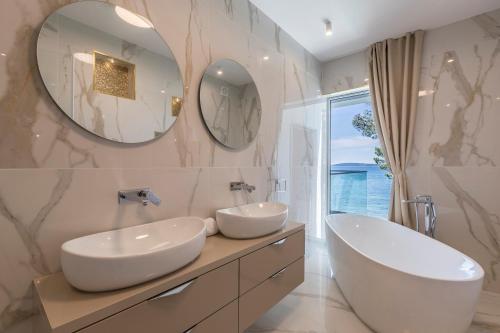 uma casa de banho com 2 lavatórios e um espelho grande em Glamorous Kastela Villa 4 Bedrooms Villa Seafront Paradise Private Pool Overlooking Sensational Sea Views Split em Kaštela