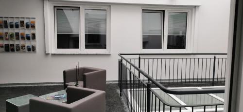 a balcony with two chairs and a table and two windows at Feel Good Hotel in Chemnitz