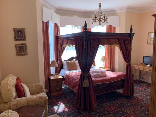 a bedroom with a canopy bed and a chair at The Redcliffe Hotel in Scarborough