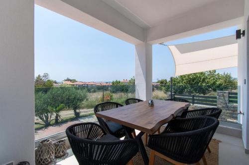 a dining room with a table and chairs and a large window at SithoniaRS Melora Luxury Apartment in Nikiti