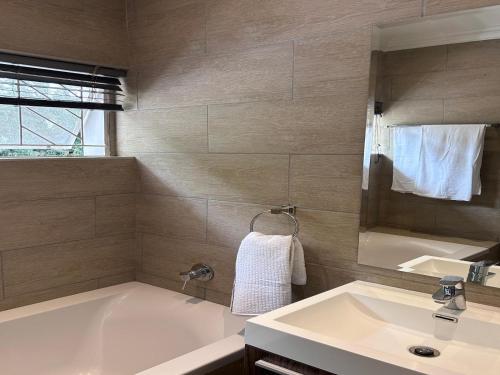 un baño con bañera y lavabo en Home Away from Home - Deluxe Queen & Twin Studio, en Johannesburgo