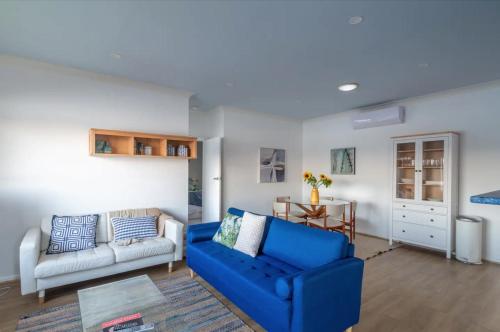 a living room with a blue couch and a table at Central Coast Jetty House in Saratoga