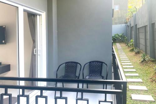 duas cadeiras sentadas na varanda de uma casa em Urbanview Hotel AnD Lampung by RedDoorz em Lampung